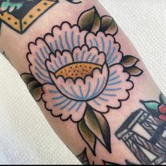 a close up of a person's arm with a flower tattoo on the forearm