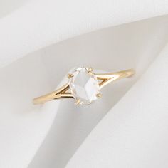 a white diamond ring sitting on top of a white cloth