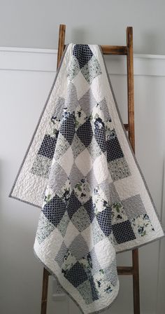 a white and black quilt sitting on top of a wooden chair