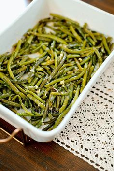 cooked green beans in a white dish on a doily