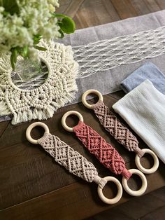 three crocheted key fobs sitting on top of a table next to a vase with flowers