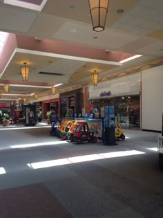 an empty shopping mall filled with vending machines and cars parked in front of them