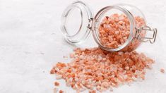 a glass jar filled with lots of pink himalayan salt sitting on top of a white surface