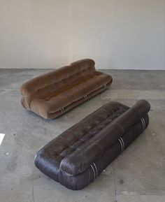 two brown leather couches sitting on top of a cement floor next to each other