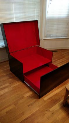 an open red box sitting on top of a wooden floor