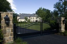 a gated driveway leading to a large house