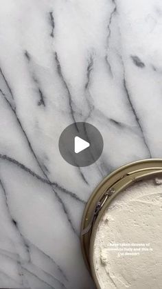 a white marble counter top with a can of paint next to it and a video play button