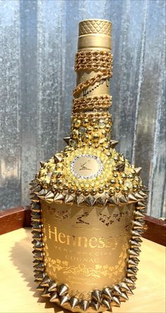 a bottle that has been decorated with gold and silver spikes on the top, sitting on a table