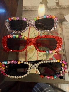 two pairs of sunglasses with beads on them sitting on top of a table next to a candle