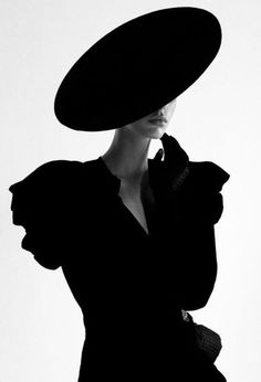 a woman in a black dress and large hat