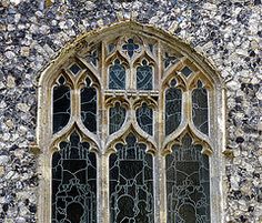 an old stained glass window on the side of a stone building with rocks around it