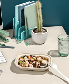 a bowl of food sitting on top of a desk next to a computer