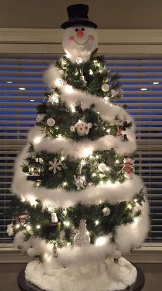 a white christmas tree decorated with lights and snowmen