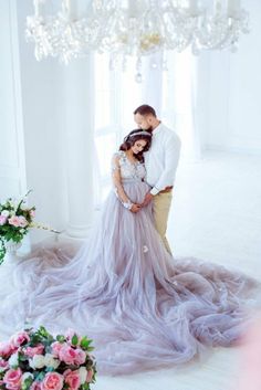 a man and woman standing next to each other in front of a chandelier