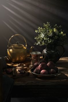 a tea pot and some fruit on a table