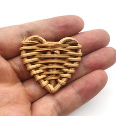 a hand holding a wooden heart shaped brooch