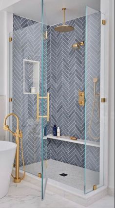 a walk in shower sitting next to a bathtub with a glass door and gold faucet