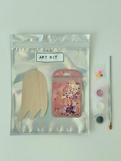 an art kit in a clear plastic bag with paint, brushes and paper angel wings