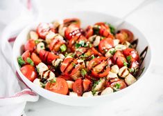 a white bowl filled with sliced tomatoes and chicken on top of a marble countertop