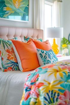 a bed with colorful pillows on it in front of a painting and window sill