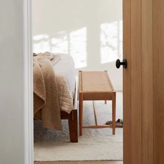 a bed sitting next to a wooden door in a room with a white rug on the floor