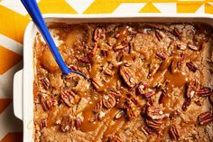 a dish with pecans and caramel drizzled on top, next to a blue spoon