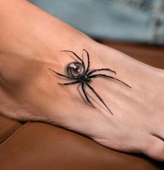 a black spider tattoo on the foot of a woman's right foot, with an eyeball in it