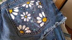 a pair of jean shorts with flowers painted on them and holes in the back pocket