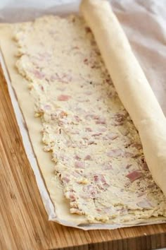 a long piece of bread sitting on top of a wooden cutting board next to a rolling pin