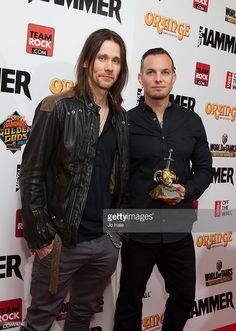 two men standing next to each other on the red carpet at an orange carpet awards event