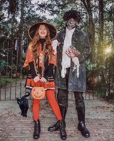 two people in halloween costumes standing next to each other on a brick walkway with trees behind them