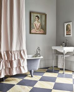 a bathroom with a checkered floor and bathtub next to a painting on the wall