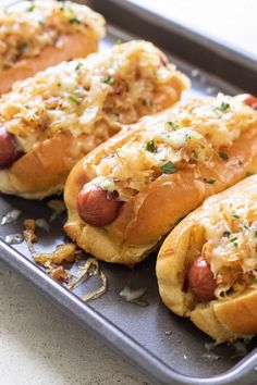 four hot dogs with toppings sitting on a pan