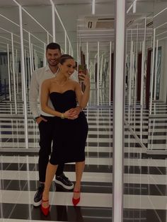 a man and woman taking a selfie in an empty room with black and white tiles