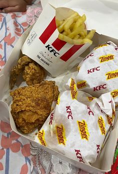 chicken and french fries in a box with kfc's wrapper next to it