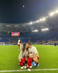 a man and woman sitting on top of a soccer field