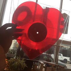 a large red heart shaped object in front of a window