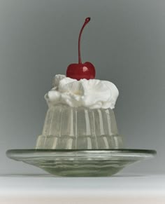 a piece of cake with whipped cream and a cherry on top is sitting on a glass plate