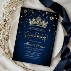 a blue and gold wedding card with a tiara on it, surrounded by flowers