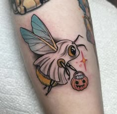 a tattoo with a bee holding a jack - o - lantern on it's arm