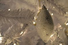 an ornament hanging from the top of a christmas tree with snow flakes