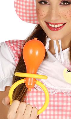 a woman in a pink and white dress is holding an orange toy with a yellow handle