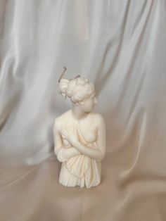 a statue of a woman with a tiara on her head sitting in front of a white background