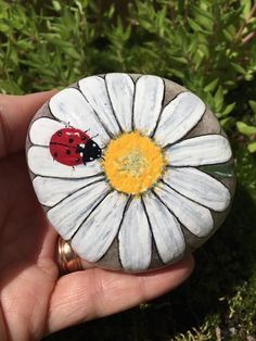 a ladybug painted on top of a rock with a flower in the middle