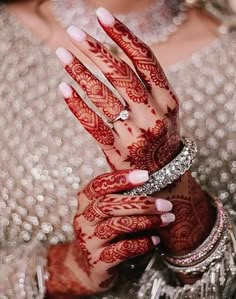 a close up of a person with henna on their hand and jewelry around her wrist