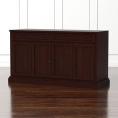 a wooden cabinet sitting on top of a hard wood floor next to a white wall