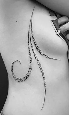 a woman's stomach with an intricate tattoo design on her side ribcage