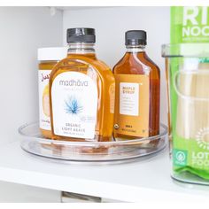 two bottles of liquid sit on a shelf next to a glass cup and another container