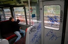 a man sitting on a bus with graffiti all over the walls and windows in front of him