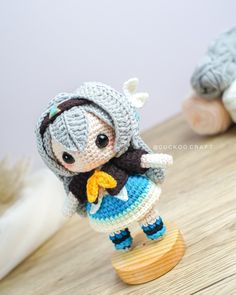 a crocheted doll is standing on a wooden stand